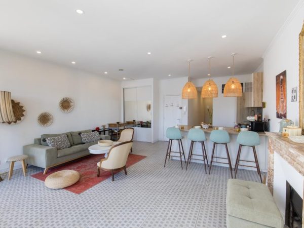 Appartement contemporain avec salon ouvert, bar de cuisine avec chaises hautes bleues et cheminée décorative en marbre.