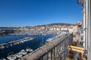 Vue panoramique sur un port de plaisance rempli de bateaux et la ville historique en arrière-plan, prise depuis un balcon.